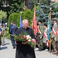 Obchody Święta Wojska Polskiego w Miechowie - ks. proboszcz Franciszek Siarek składa hołd pod Pomnikiem z Orłem